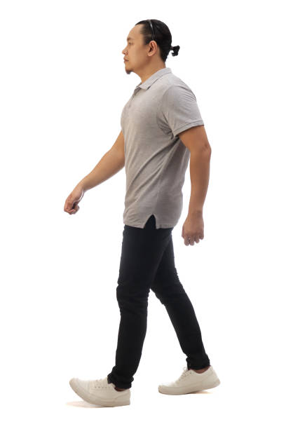 Asian man wearing casual grey shirt black denim and white shoes, walking forward, side view, happy confidence expression. Full body portrait isolated stock photo
