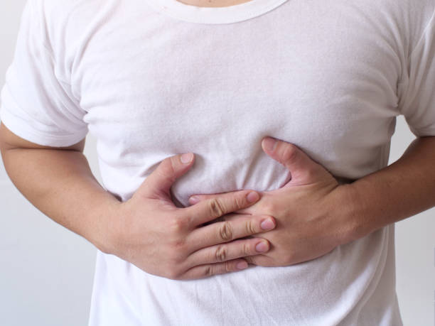 Anonymous person pushing his belly with hands due to stomach cramp pain or chronic gastritis illness stock photo