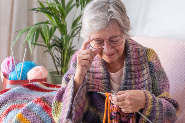 istock Senior mature woman sitting on sofa at home while knitting and looking at her work in progress. Hobby, retirement, relax concept for elderly female grandmother wearing glasses 1370468694