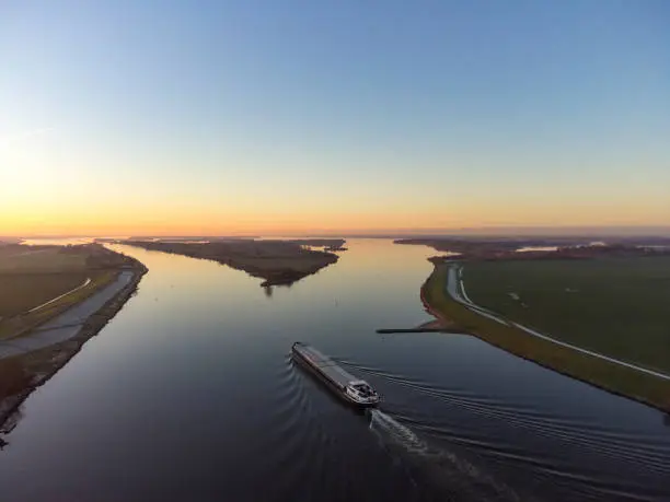 Aerial view on a ship sailing on the river Ijssel during sunrset during a cold winter afternoon in Overijssel, Netherlands.