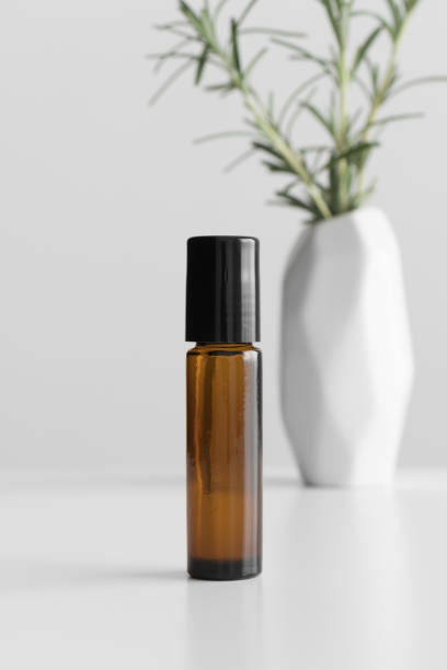 istock Amber glass roll-on bottle mockup with a rosemary on the white table. 1370468923