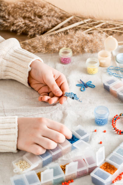 istock The girl's hands are weaving a dolphin on a table with items for beading. Development of creative skills and fine motor skills for children. Top and vertical view. 1370469894