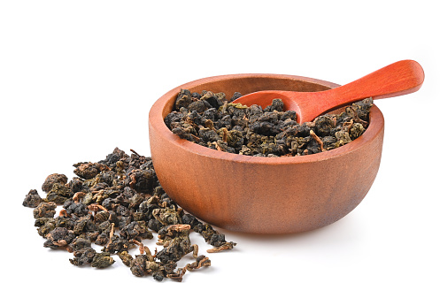 Chinese oolong tea Tie GuanYin in wooden bowl and spoon isolated on white background.