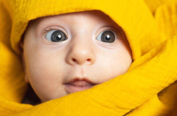 赤ちゃんの顔は黄色い赤ちゃんスワドルに包まれています。 - baby people headband portrait ストックフォトと画像