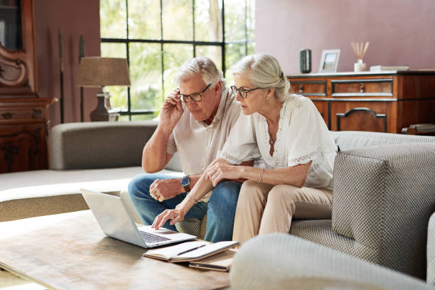 집에서 함께 재정을 계산하는 동안 노트북을 사용하여 성숙한 부부의 샷 - pension retirement planning savings 뉴스 사진 이미지