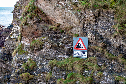 Danger falling rocks sign on side of cliff