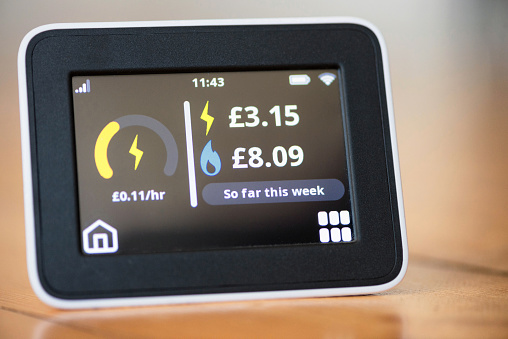 Close-up of a smart meter in a UK home, showing electricity and gas expenditure figures for the month.