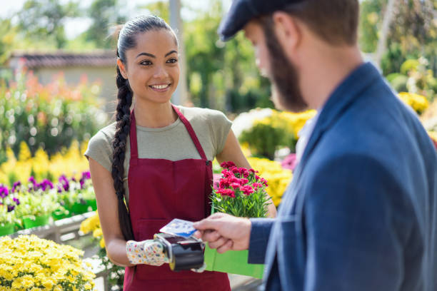 istock Young gardener selling flowers to client 1370473124