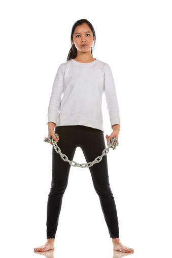 Woman standing with a steel chain wrapped around her fists.