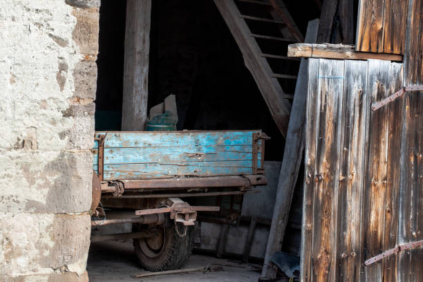An old wooden trailer stands in a barn