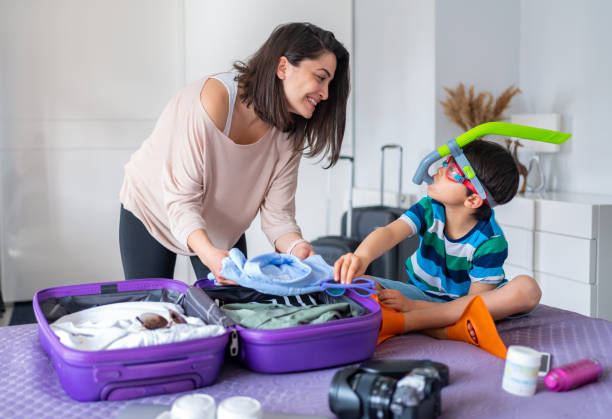 Packing For Holiday Mother And Son Preparing Travel Suitcase On Bed At Home packing stock pictures, royalty-free photos & images