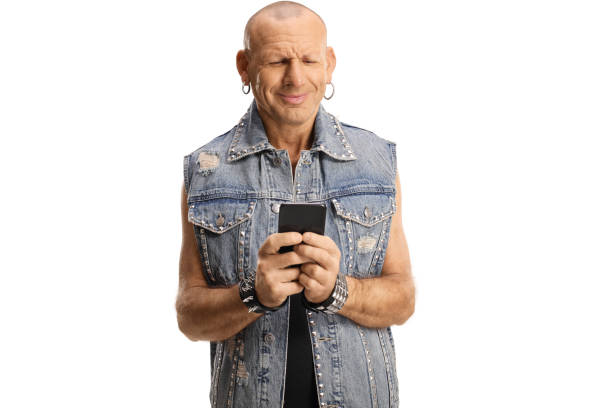 Bald punk in a denim vest using a smartphone isolated on white background