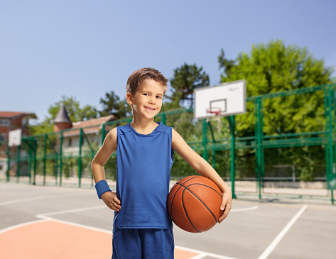 Portrait of a boy holding a basketball ball at a sports court