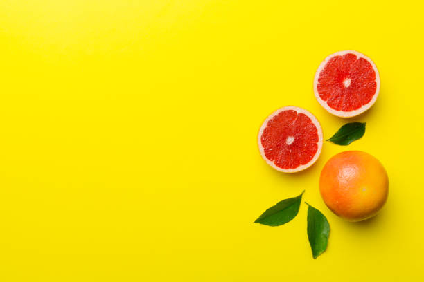 istock fresh Fruit grapefruit with Juicy grapefruit slices on colored background. Top view. Copy Space. creative summer concept. Half of citrus in minimal flat lay with copy space 1370476511