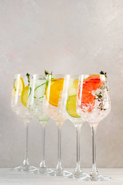 istock Gin and tonic cocktails set. Trendy Alcoholic drinks with lime, lemon, grapefruit, orange, cucumber, soda and spicy herbs in wine glasses, gray background. Summer cocktail party 1370479577