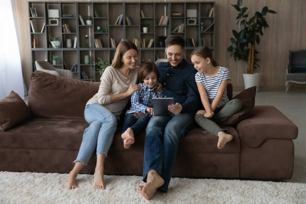 istock Happy family with children using tablet together, relaxing on couch 1370480852