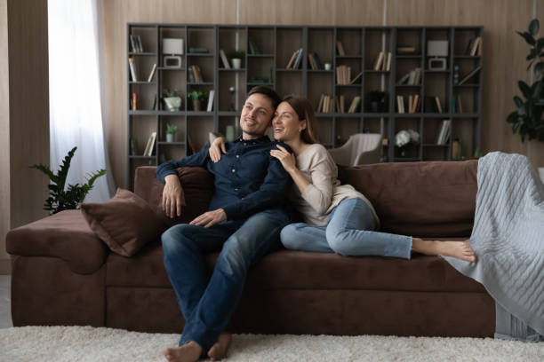 istock Happy Caucasian couple hugging, relaxing on couch, dreaming together 1370480910