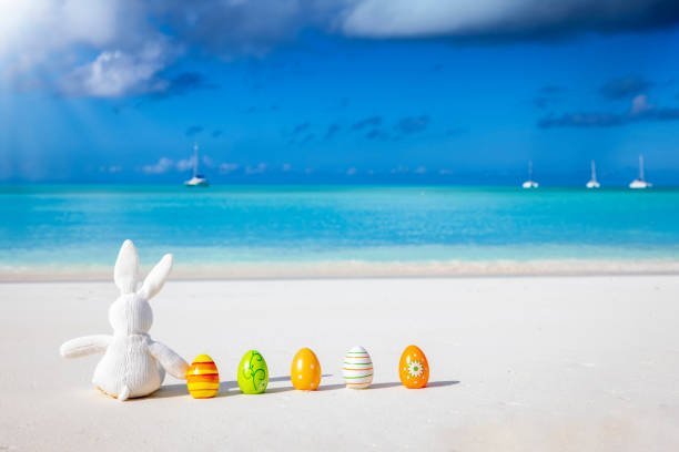 istock A bunny and colorful eggs sitting on a tropical paradise beach 1370482590