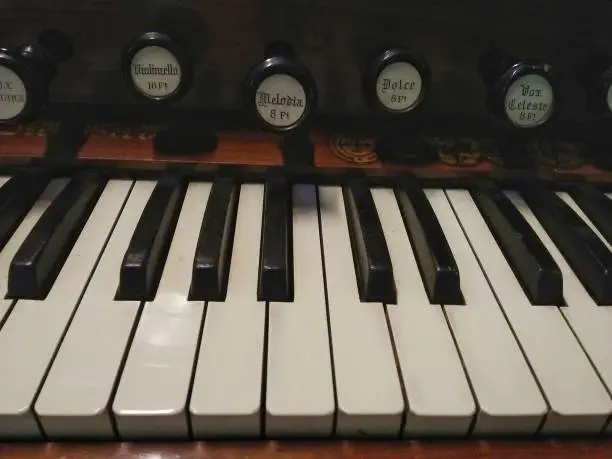 Photo of Close up of an old piano keyboard with wooden background. Vintage Looks/Style.
