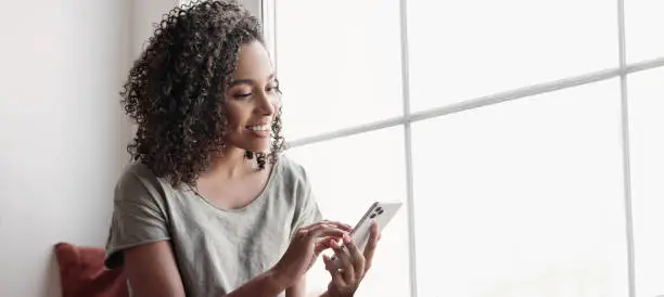 Photo of Young woman using smartphone, relaxing at home