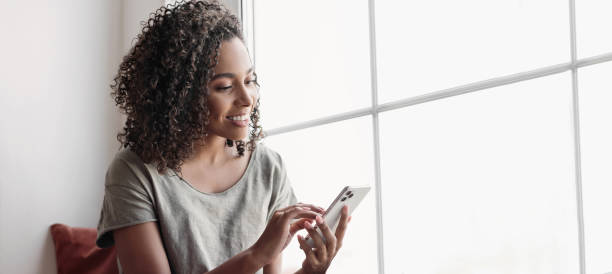 young woman using smartphone, relaxing at home - calling imagens e fotografias de stock