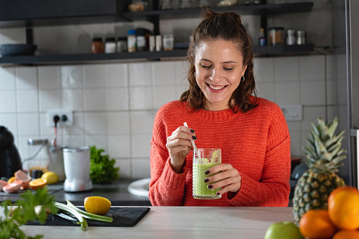 Portrait of healthy young Caucasian woman drinking the green smoothie