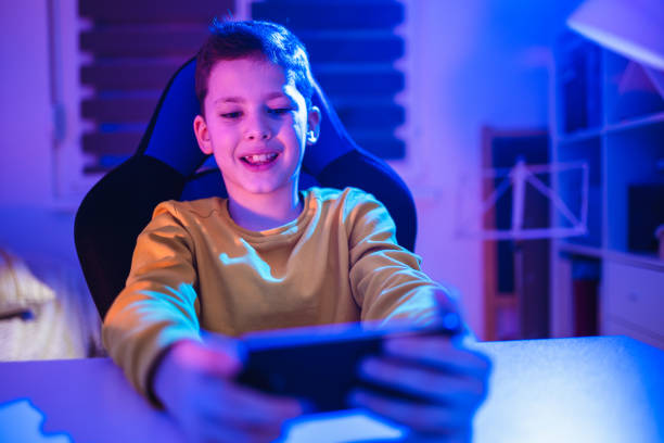 istock Boy playing videogame on smartphone in the evening at home 1370485729