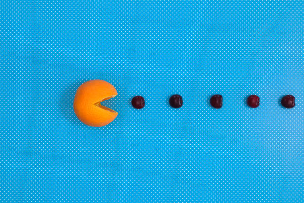 Creative concpet of orange eating cherries onvibrant blue background. Flat lay pac man
