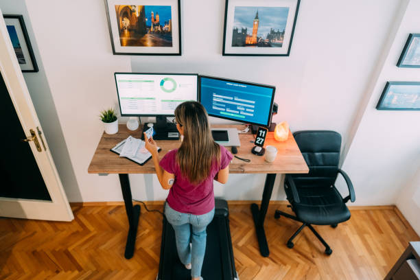 istock Woman working at standing desk is using credit card while walking at treadmill 1370488584