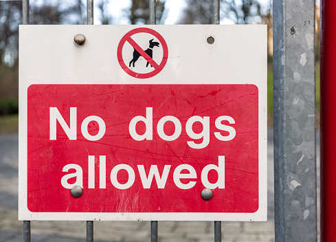 A sign in a public park, warning that dogs are excluded from an area.