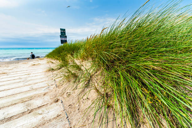 Wooden pathway marks the access to Kilmore beach, County Wexford. A boardwalk grants access at an Irish Atlantic ocean strand conveying environment preservation concept or Irish vacation illustration. Kilmore Quay, County Wexford, Ireland un camino de madera marca el acceso a la playa de kilmore, condado de wexford. un paseo marítimo otorga acceso a una hebra del océano atlántico irlandés que transmite el concepto de preservación del medio ambiente o la ilustración de vacaciones irlan