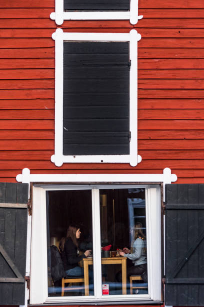 Hudiksvall, Sweden Feb 9, 2022 Girls eating lunch in a window of a cafe in a row of red warehouses on the Sundskanal in downtown.
