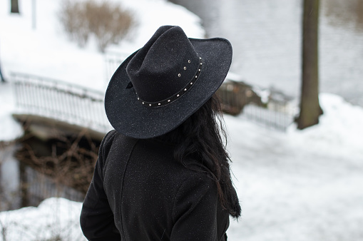 People from behind. woman in black clothing and cowboy hat from behind in winter