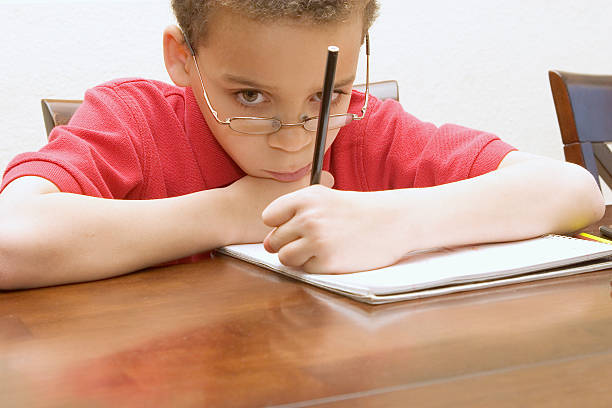 Young boy reluctant to do homework stock photo