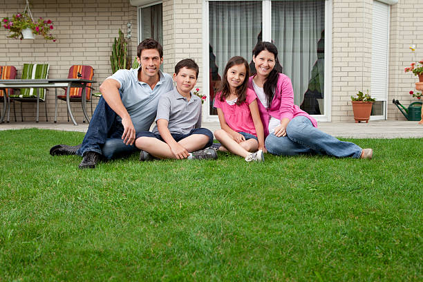 Young family sitting in front of their home