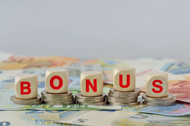 Wooden blocks with the word Bonus on coins and banknotes - Concept of economic bonus and financial aid stock photo