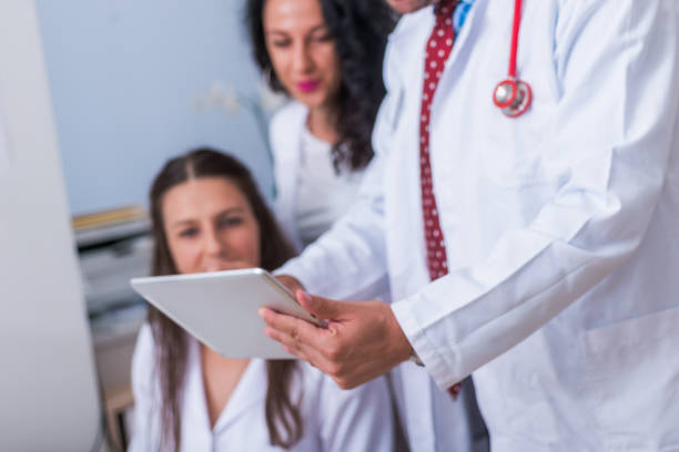 istock Two nurses ( female physicians ) and a male doctor looking in a tablet at the doctor's office while discussing a medical report ( patient's health problems ). 1370509534