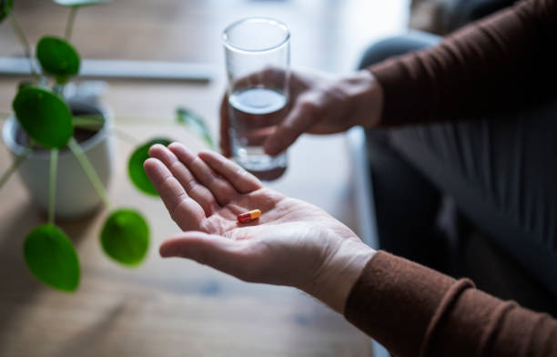 istock Hands holding pills and water glass. 1370510866