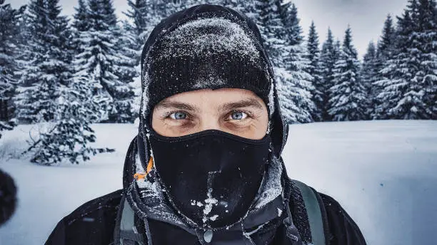 Portrait of smiling snowboarder covered in snow and looking at the camera.