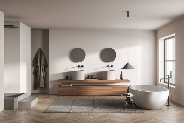 istock Bright bathroom interior with two round mirrors, window, bathtub 1370512357