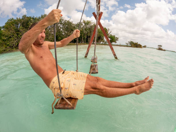 istock Young man having fun on swing in a beautiful lagoon on a sunny day 1370512664