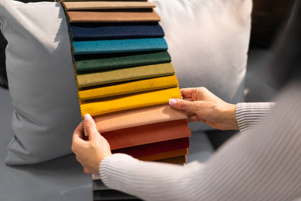 la mujer elige la tela en el sofá. una mujer joven observa muestras de tejido. - textured upholstered choice colors fotografías e imágenes de stock