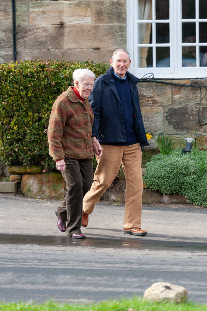istock Elderly couple holding hands as they cross a road in a rural setting 1370512954