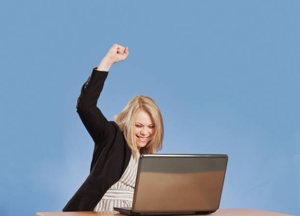 istock Overjoyed woman punches the air as she succeeds on her laptop computer 1370513083