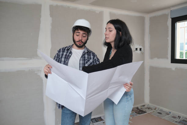 istock Architect shows apartment in construction blueprints to interested young woman. 1370515531