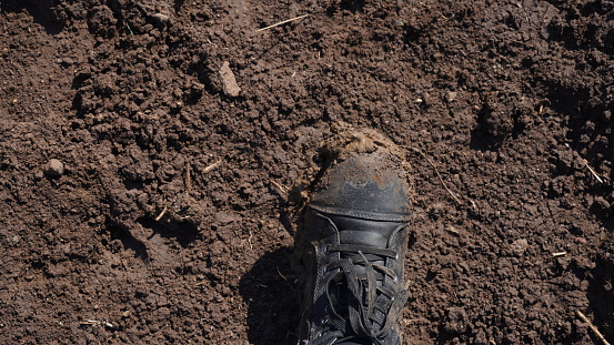 Women boots in the mud, detail of dirty boots and muddy, walk. Top down dirty black laced boots woman in blue jeans.