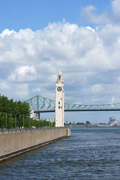 Montreal clock tower located at the entrance of the old port (Quai de l'Horloge). Also called Victoria Pier or Sailors Memorial Clock, the clock tower was dedicated to Canadian sailors who died in First World War. In the background Jacques Cartier Bridge crossing river Saint Lawrence.