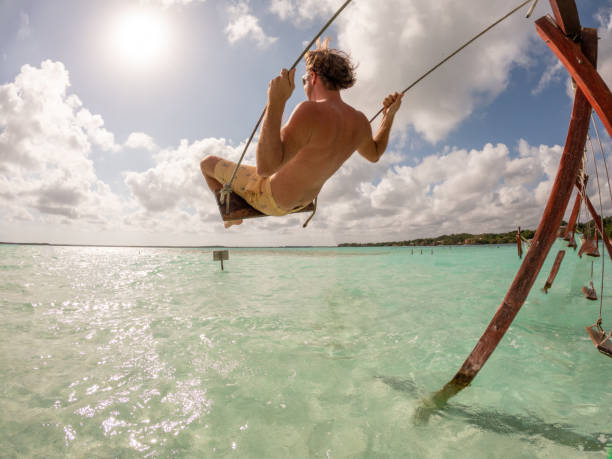 istock Young man having fun on swing in a beautiful lagoon on a sunny day 1370517038