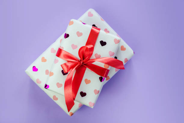 istock Gift boxes wrapped in heart pattern paper with red ribbon bow on pink background 1370517104