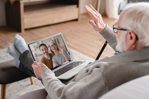Old elderly pensioner man grandfather having videocall conversation meeting virtual conference with his family, grandchildren, children on digital tablet online remotely on distance